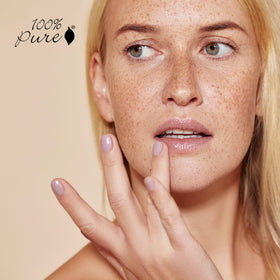 100% PURE lip balm held in hand showing compact size for on-the-go use