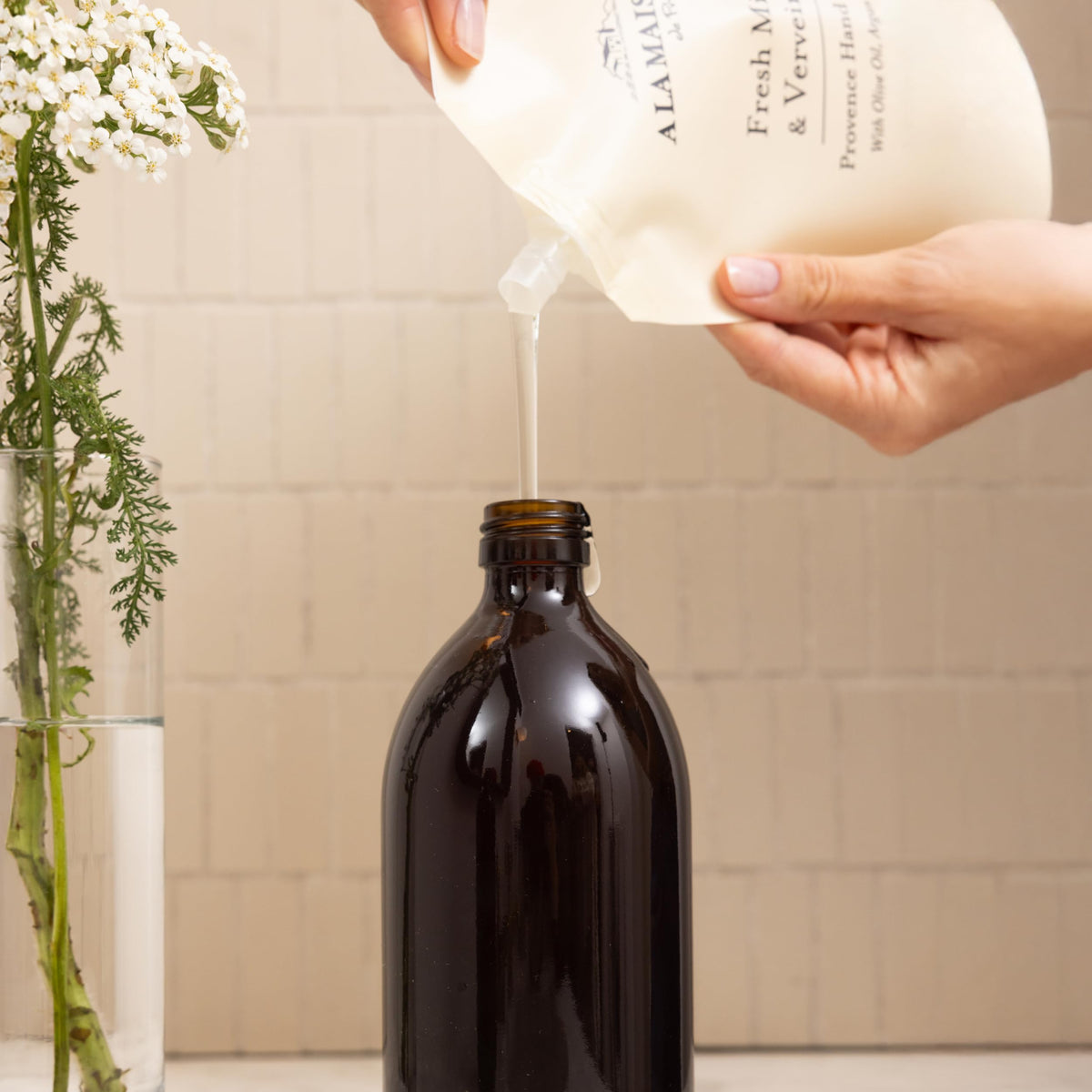 A LA MAISON pouring refill into bottle showing easy, low-waste refill