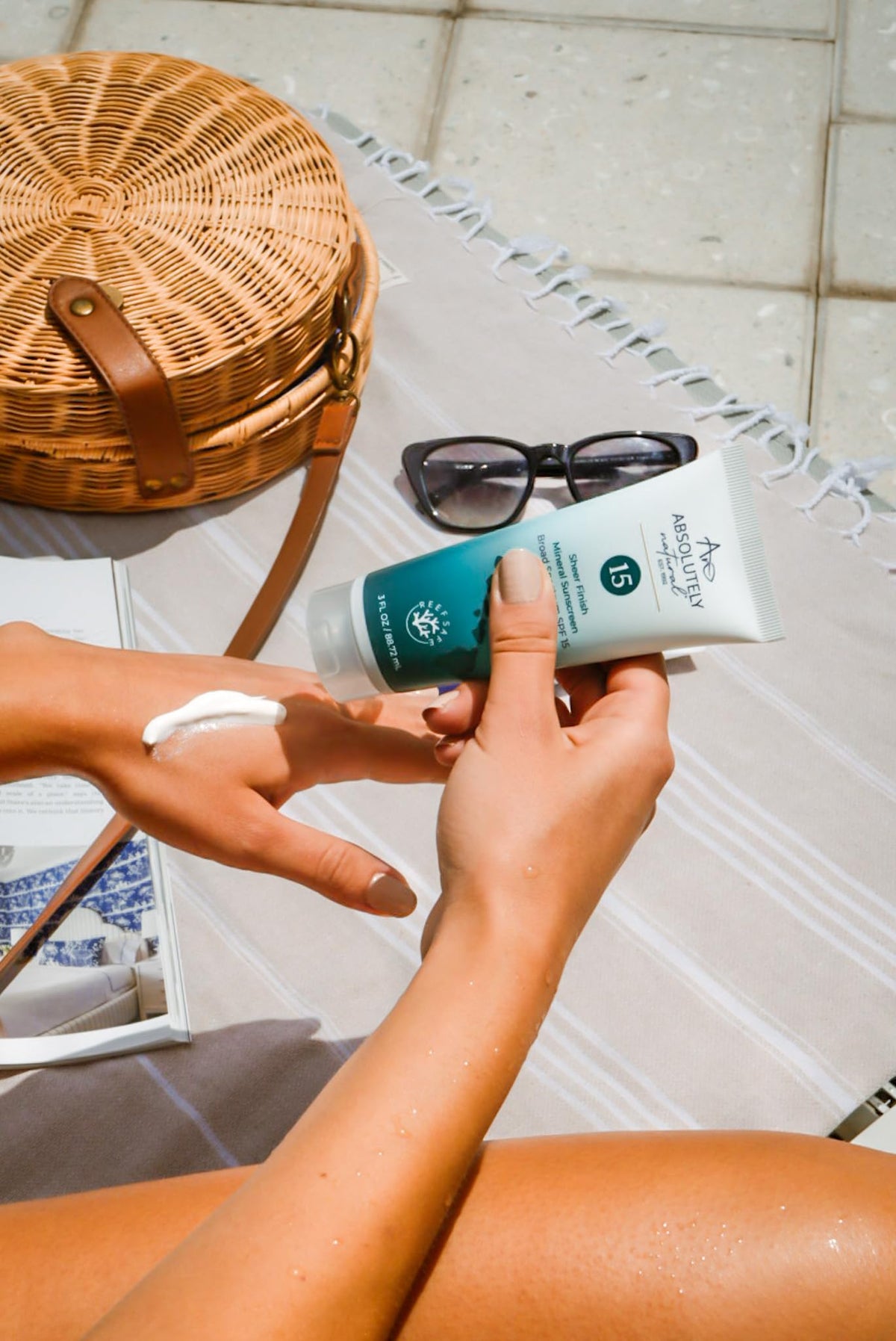 Absolutely Natural 3 oz tube beside sunglasses showing compact travel-friendly benefit