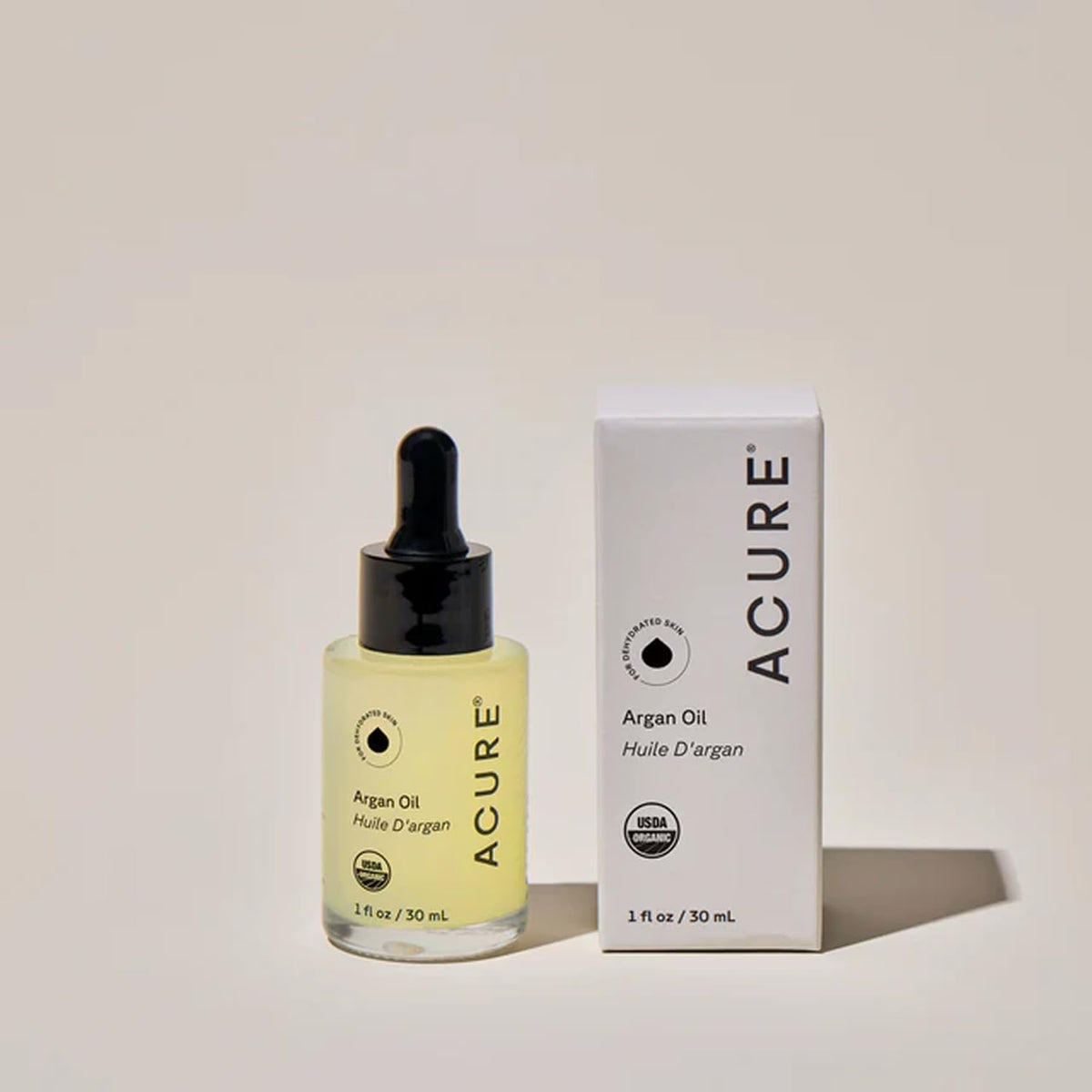 Drop of Acure argan oil on fingertip before facial application for hydration