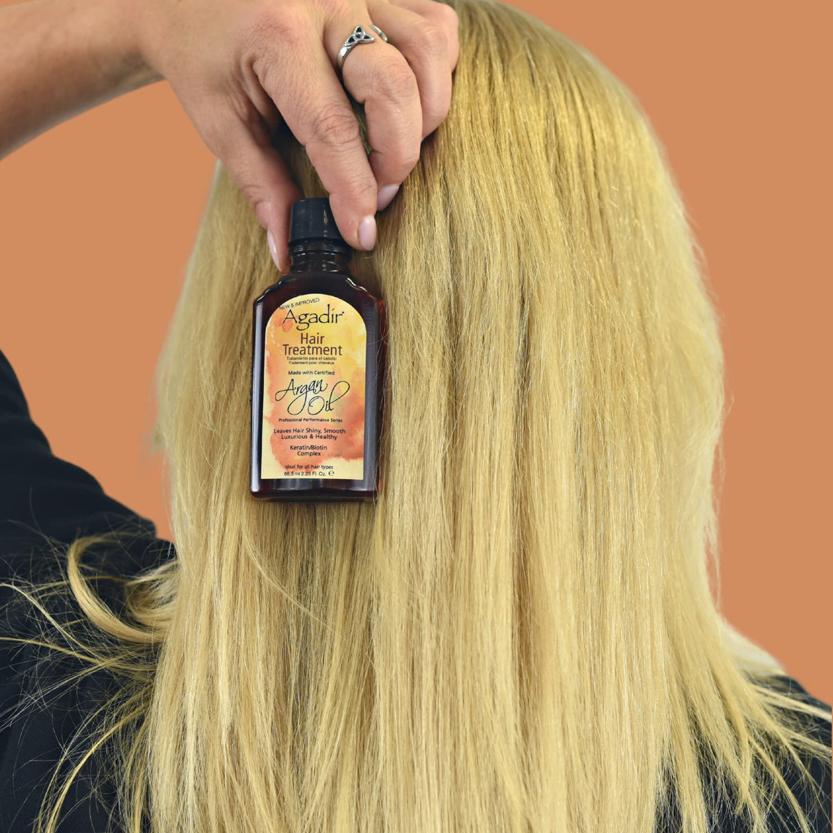 Agadir oil in palm being applied to hair showing easy smoothing benefit