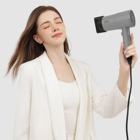 AINA hair dryer held in hand to show scale and travel-friendly size