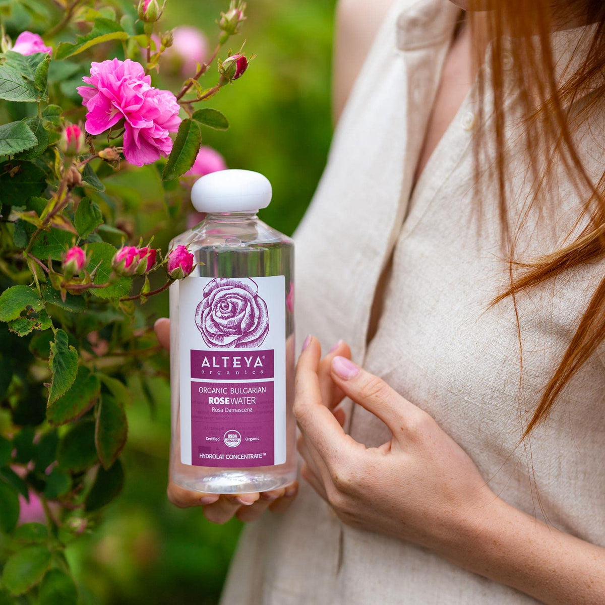 Alteya Organics bottle surrounded by fresh rose petals for purity