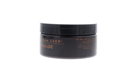 American Crew pomade next to toiletry items showing travel-friendly size