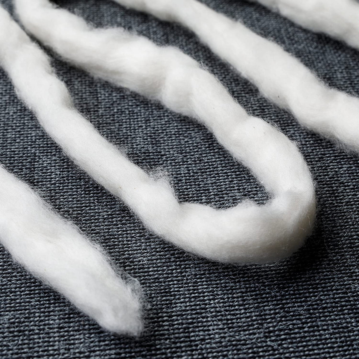 AMOZA cotton beside a hand to show scale and ease of use for precise tasks