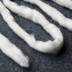 AMOZA cotton beside a hand to show scale and ease of use for precise tasks