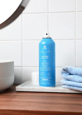 Andis spraying Cool Care Plus onto clipper blade to clean and cool