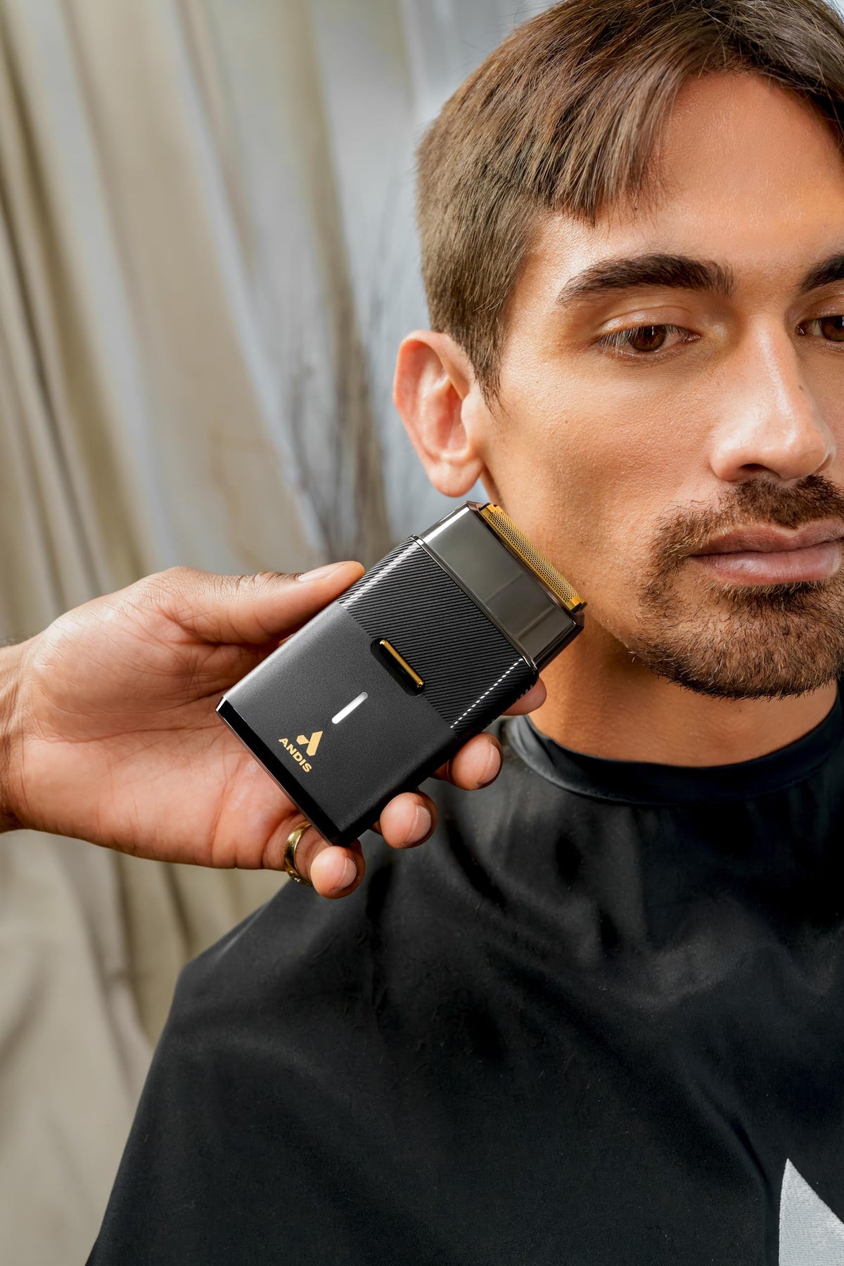 Andis shaver in hand for scale to show compact size and travel-friendly portability