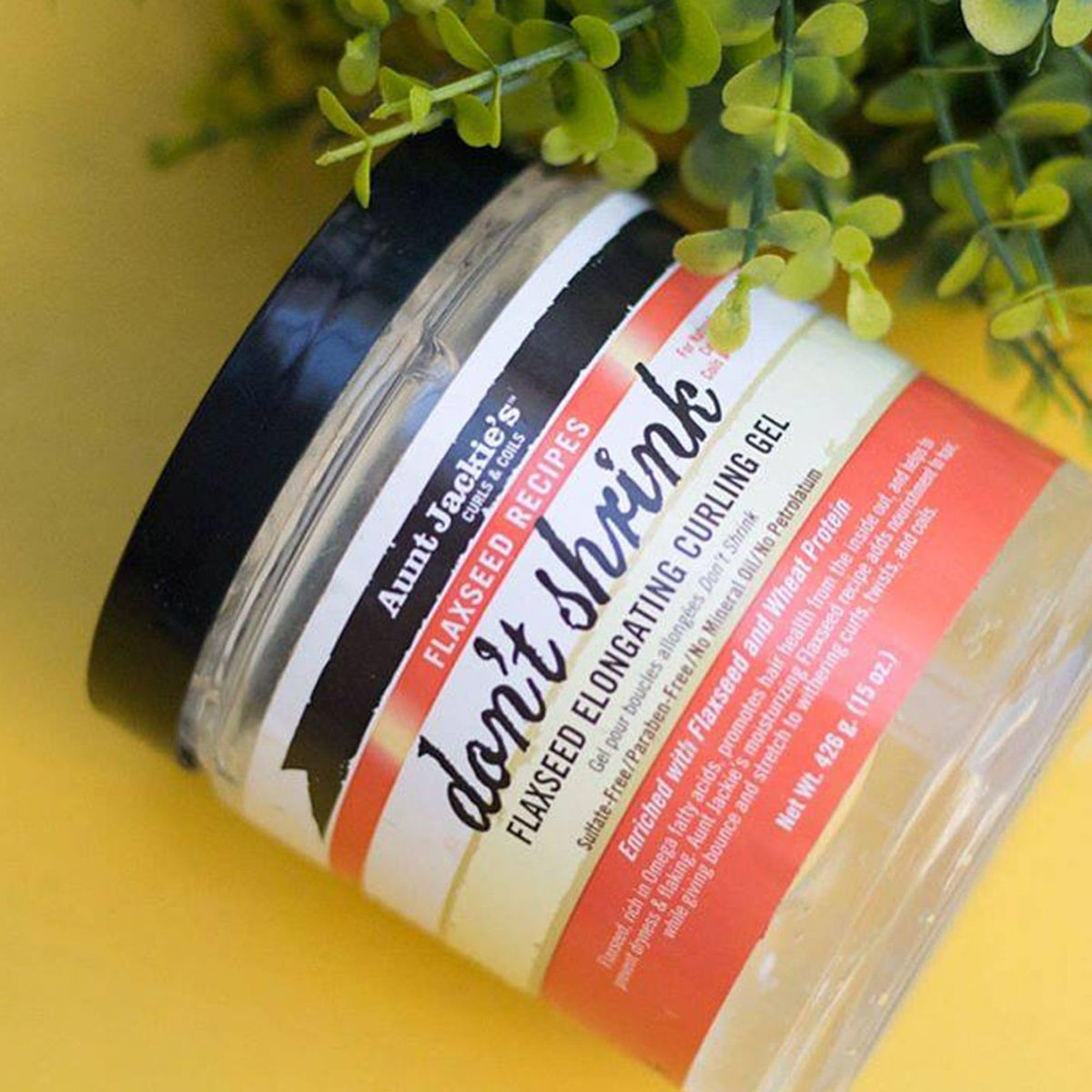 Hand holding Aunt Jackie's 15 oz jar to show scale and travel-friendly convenience