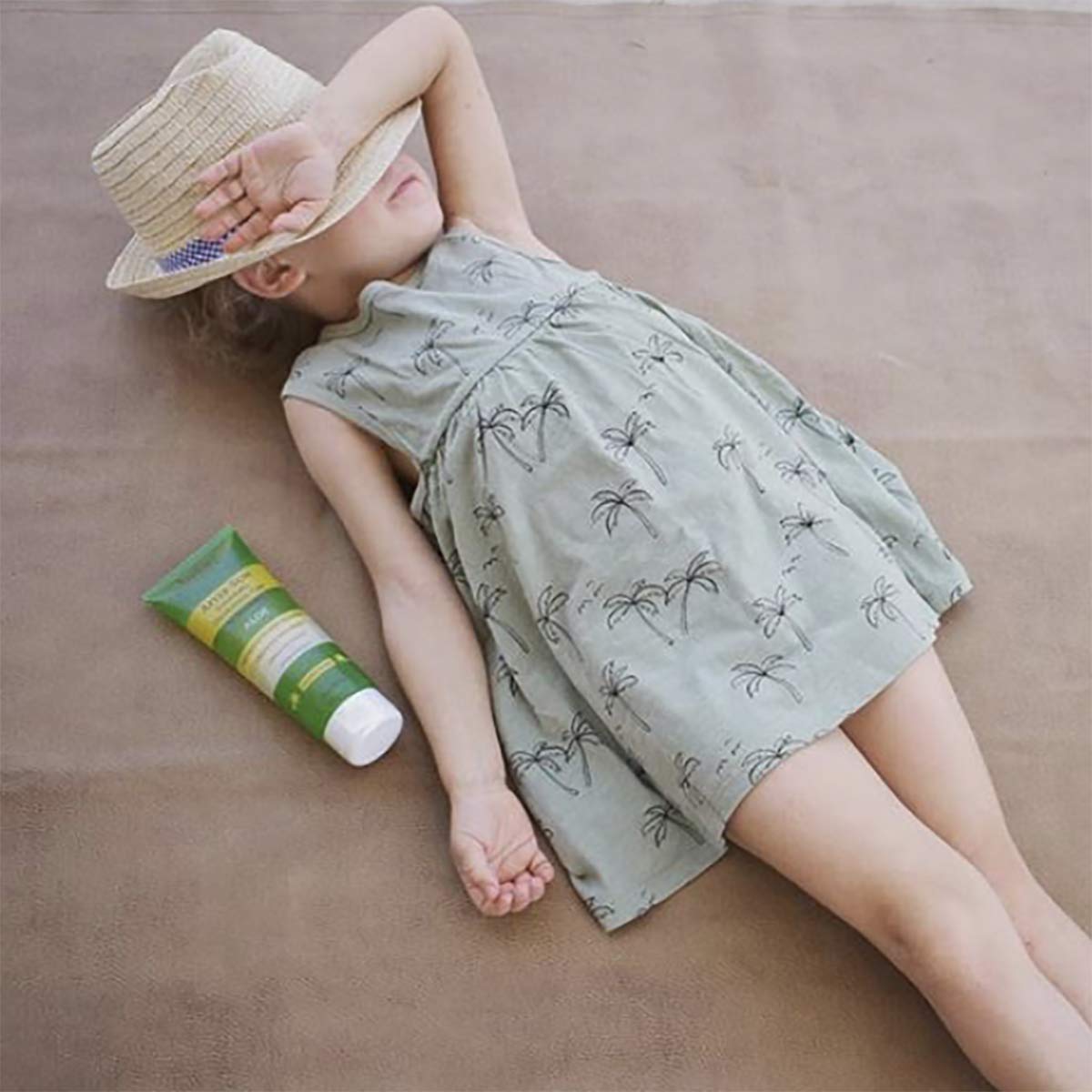 Babo Botanicals tube on beach towel showing soothe-and-rehydrate lifestyle benefit