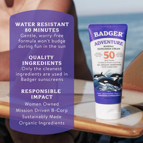 Athlete applying Badger sunscreen on beach near surfboard showing water-resistant benefit