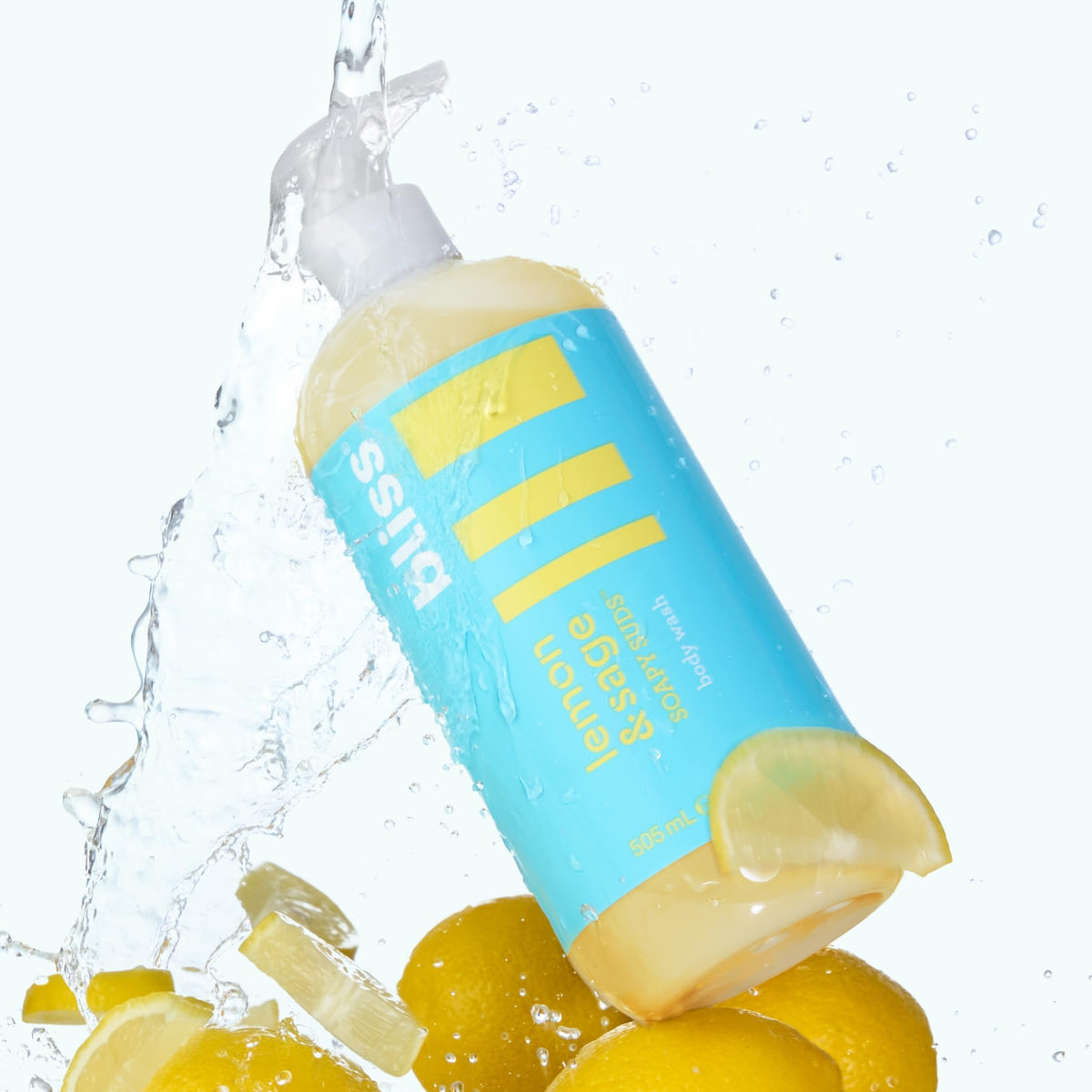 Fresh lemons and sage sprigs beside Bliss evoking citrus-herbal fragrance notes