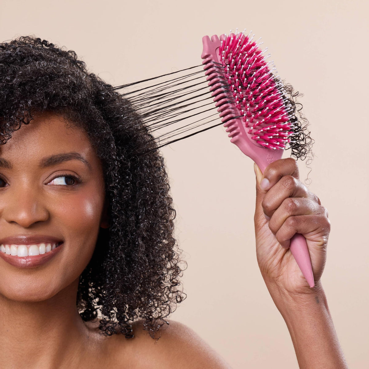 Bounce Curl brush held in hand to show scale and portability for styling on-the-go and home use