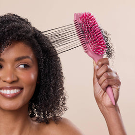 Bounce Curl brush held in hand to show scale and portability for styling on-the-go and home use