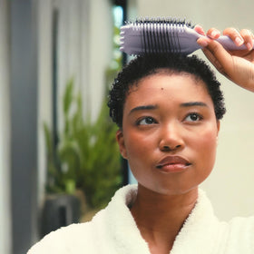 Bounce Curl model using brush to lift roots and define coils for voluminous finish