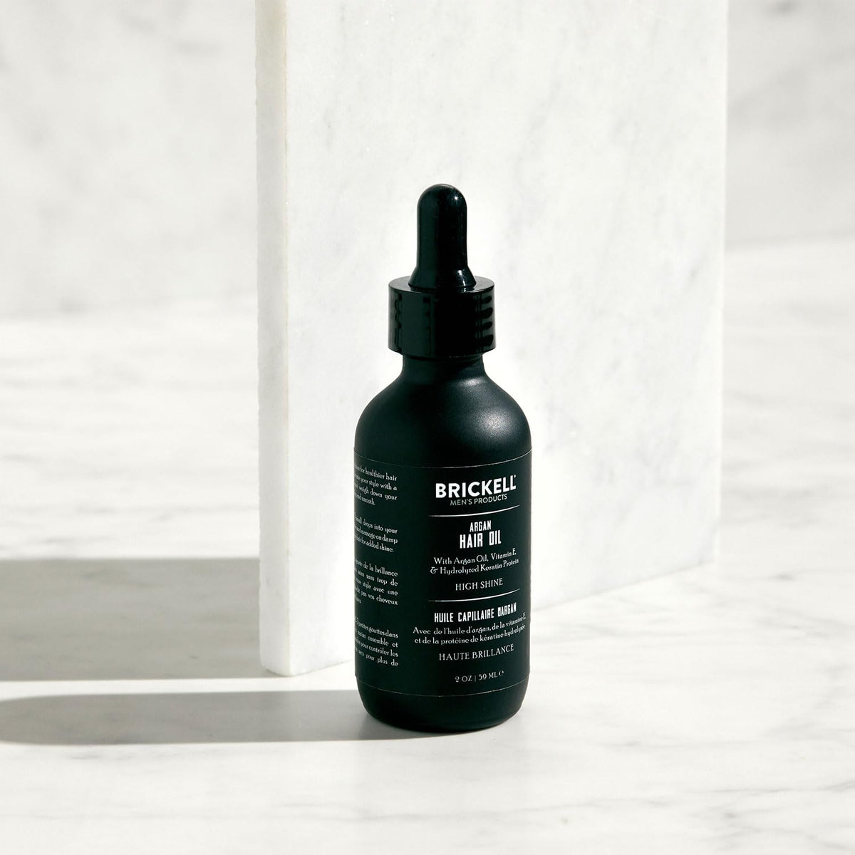 Brickell applying oil to hair ends to tame frizz and increase shine