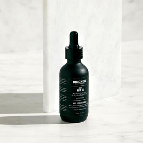 Brickell applying oil to hair ends to tame frizz and increase shine