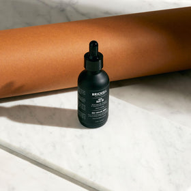 Brickell 2 oz bottle beside ruler to show compact travel-friendly size