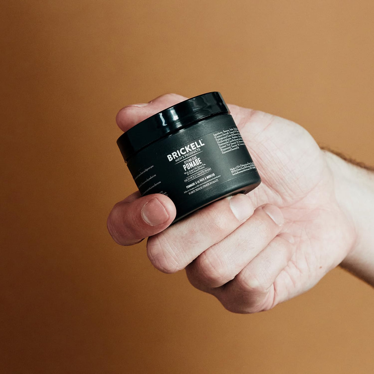 Brickell hands applying pomade demonstrating easy workability and pliable hold