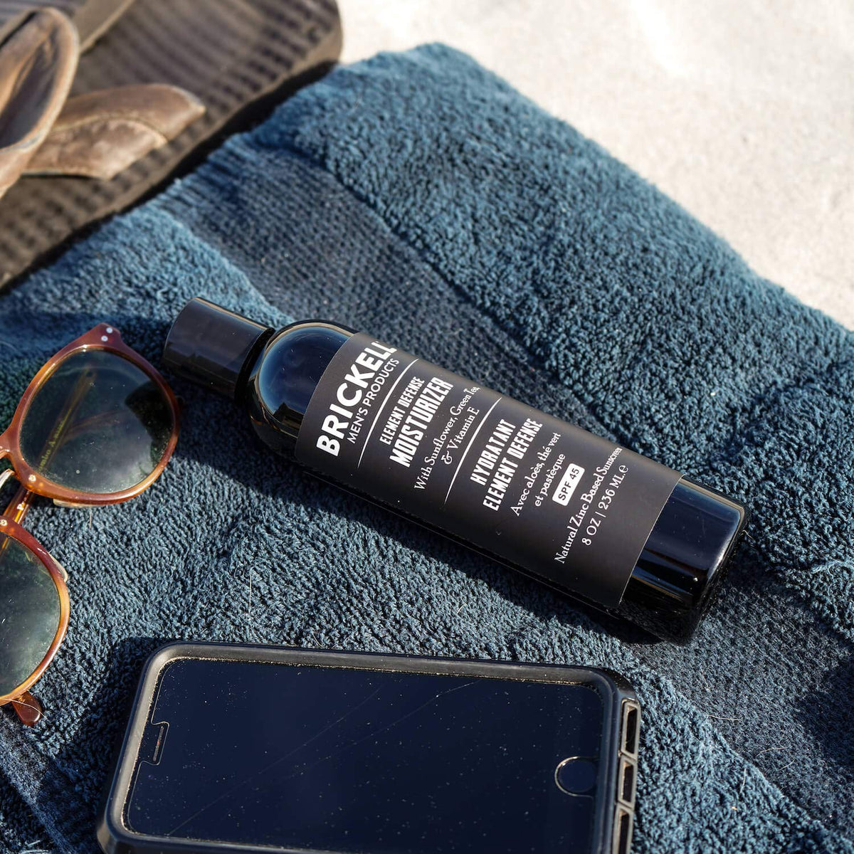 Brickell Men’s product in beach setting illustrating broad-spectrum sun protection benefit