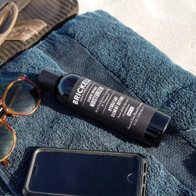 Brickell Men’s product in beach setting illustrating broad-spectrum sun protection benefit