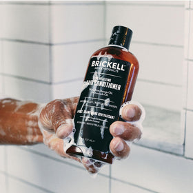 Brickell Men's Products conditioner being applied in shower for improved manageability benefit
