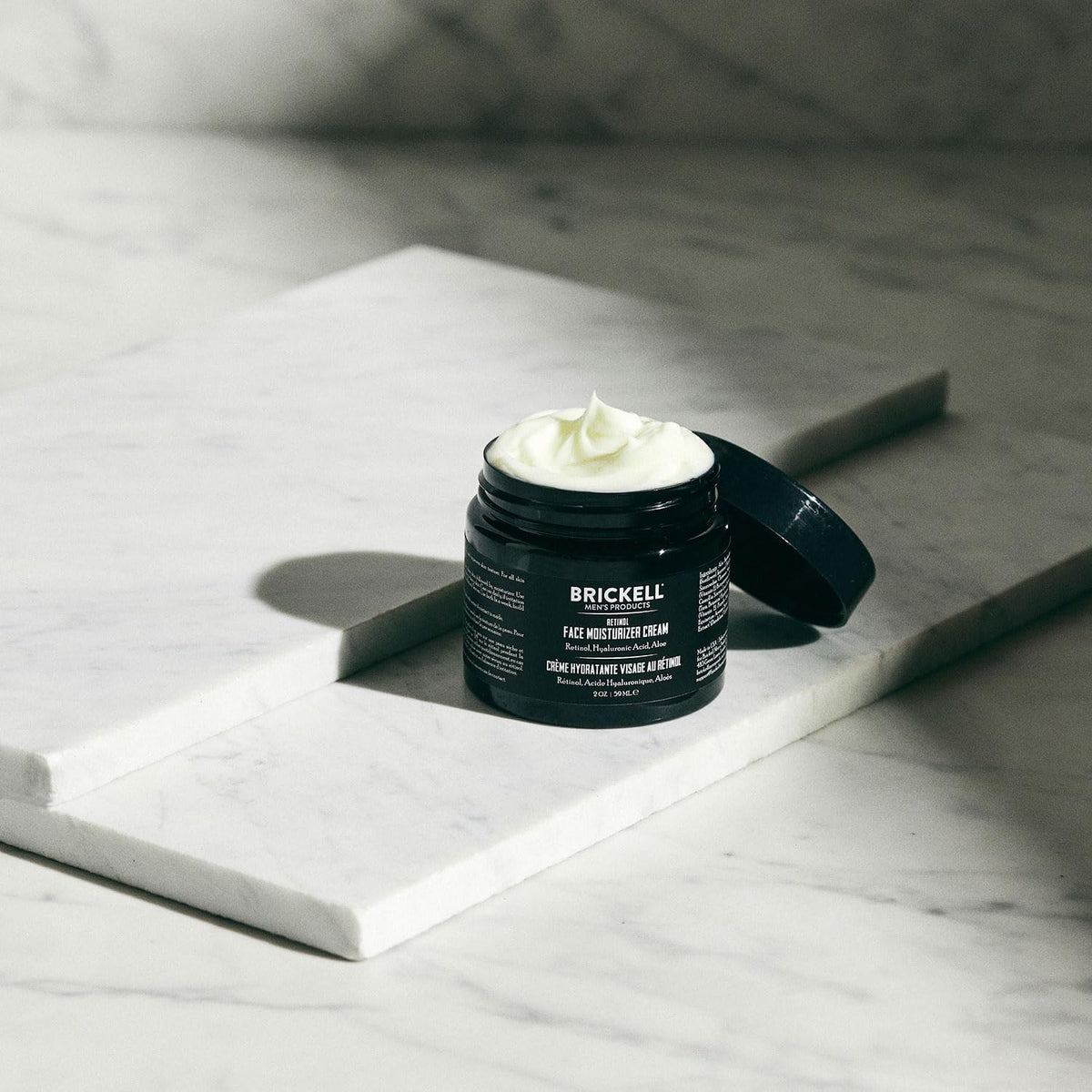 Brickell Men's Products next to a coin showing 2 oz size and travel-friendly benefit