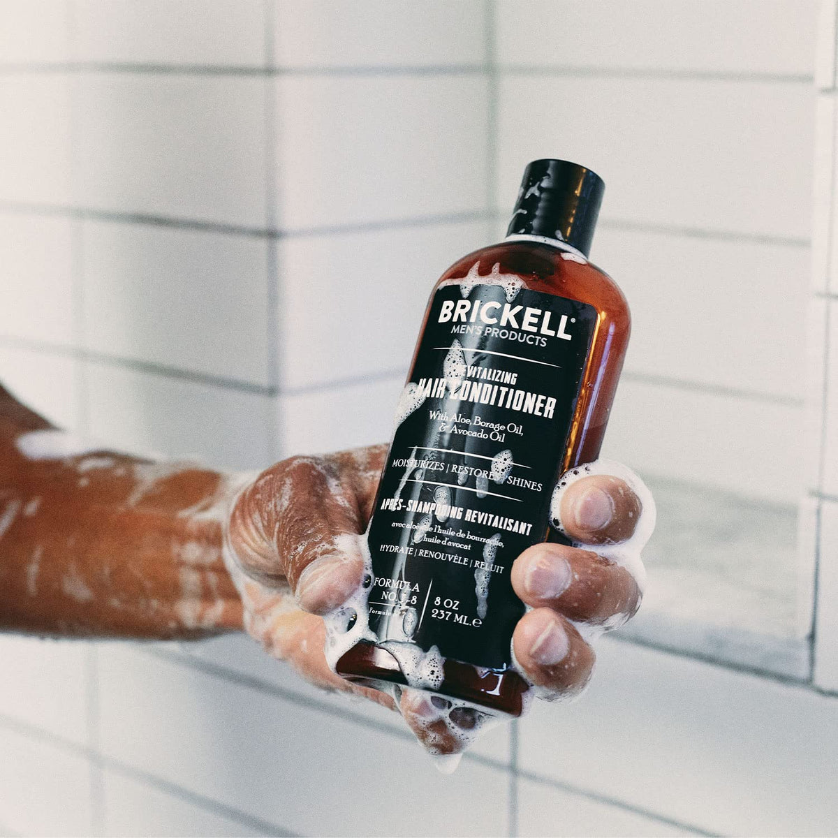 Brickell Men's Products bottle held in hand for size comparison and travel-friendly benefit