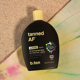 b.tan 12oz bottle beside a hand for size and usage clarity