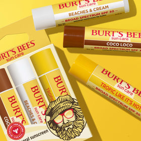 Burt's Bees in use on a beach applying balm to lips for sun care during outdoor activities