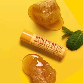 Burt's Bees tube beside coin showing compact size for pockets and portability