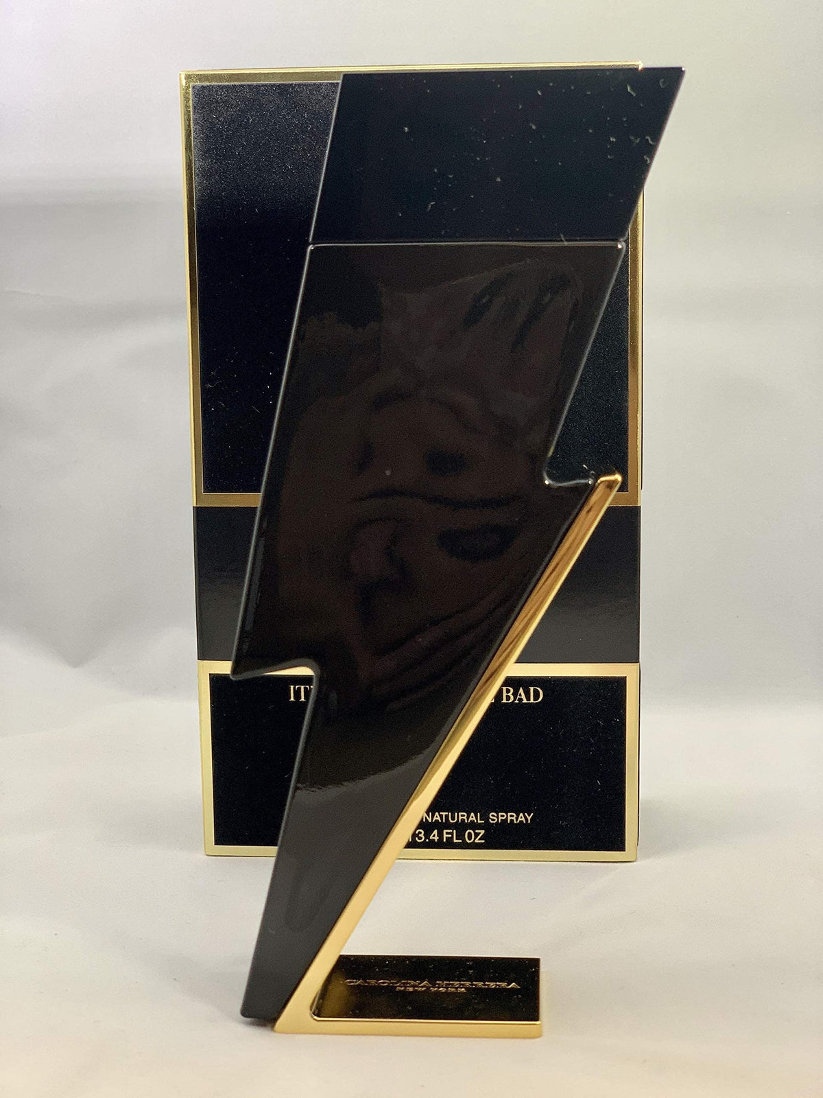 Carolina Herrera Bad Boy size comparison next to wallet shows 3.4 oz scale advantage