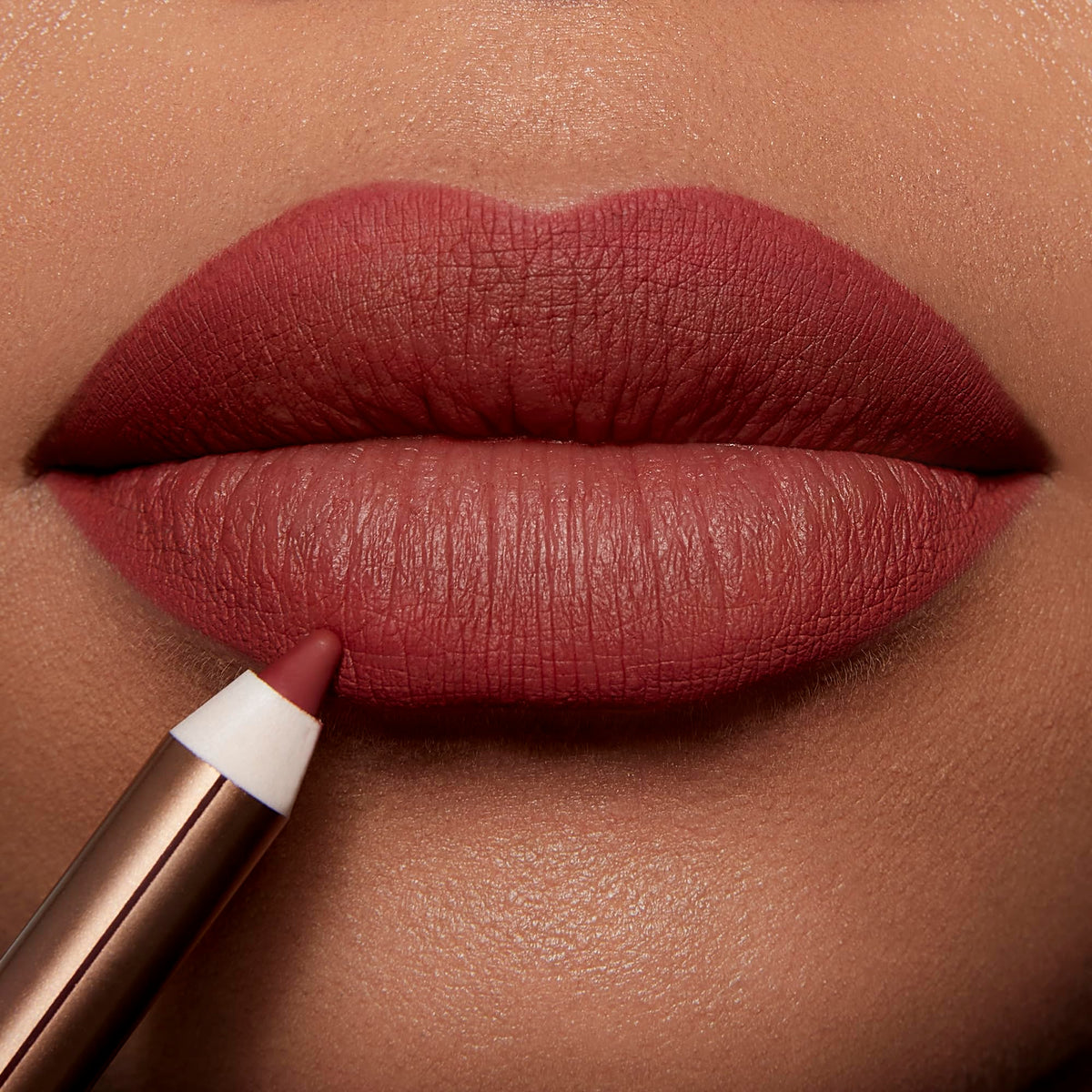 Charlotte Tilbury pencil in use outlining lips to create fuller-looking shape