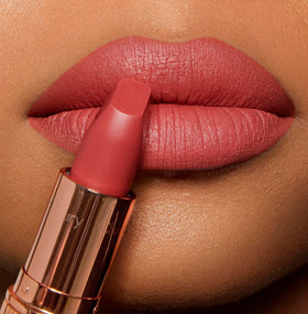 Charlotte Tilbury Sexy Sienna lip swatch on model shows wearable golden-coral color benefit: brightens complexion