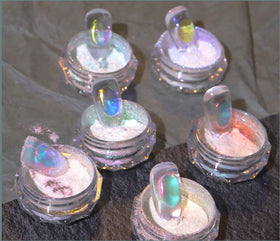 CHARMING MAY powder swatched on black gel showing intense neon holographic shift