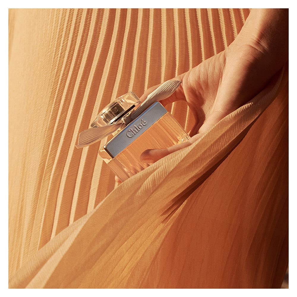 Chloe New By Chloe next to everyday items showing 1.6 oz scale and travel-friendly benefit