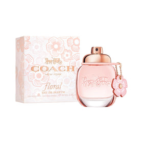 Coach bottle in a sunlit field setting conveying fresh floral mood