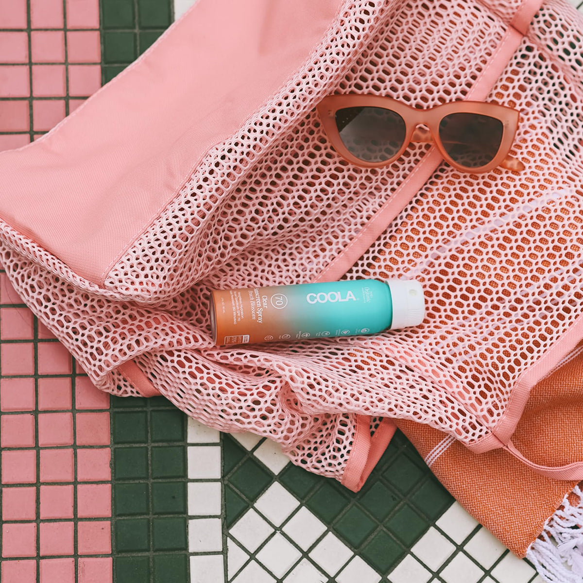 COOLA spray in hand demonstrating easy application and even coverage benefits