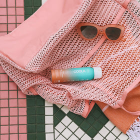 COOLA spray in hand demonstrating easy application and even coverage benefits