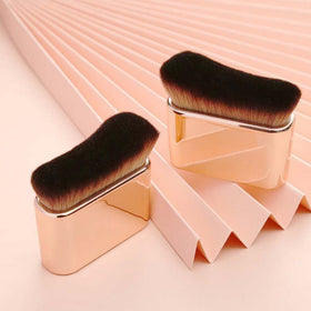 COSHINE brush held in hand to show compact size and control for body and face