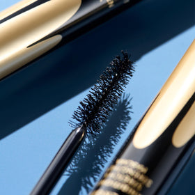 COVERGIRL tube next to coin to show compact travel-friendly size