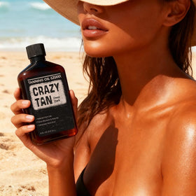 Crazytan bottle beside sunbather at beach conveying outdoor tanning use