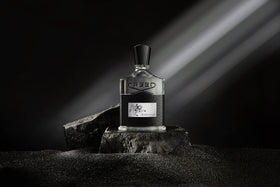 Creed Aventus bottle next to a hand for scale benefit: clear idea of 100 ml size