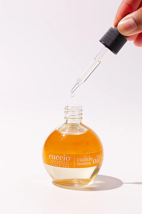 Cuccio bottle beside cold-pressed oil ingredients for natural benefit