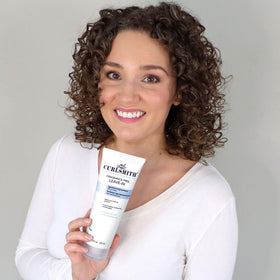 CURLSMITH 8 oz bottle next to hand to show compact travel-friendly size