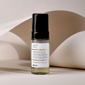 Davines Liquid Spell held in hand for size comparison, showing travel-friendly 4.23 fl oz