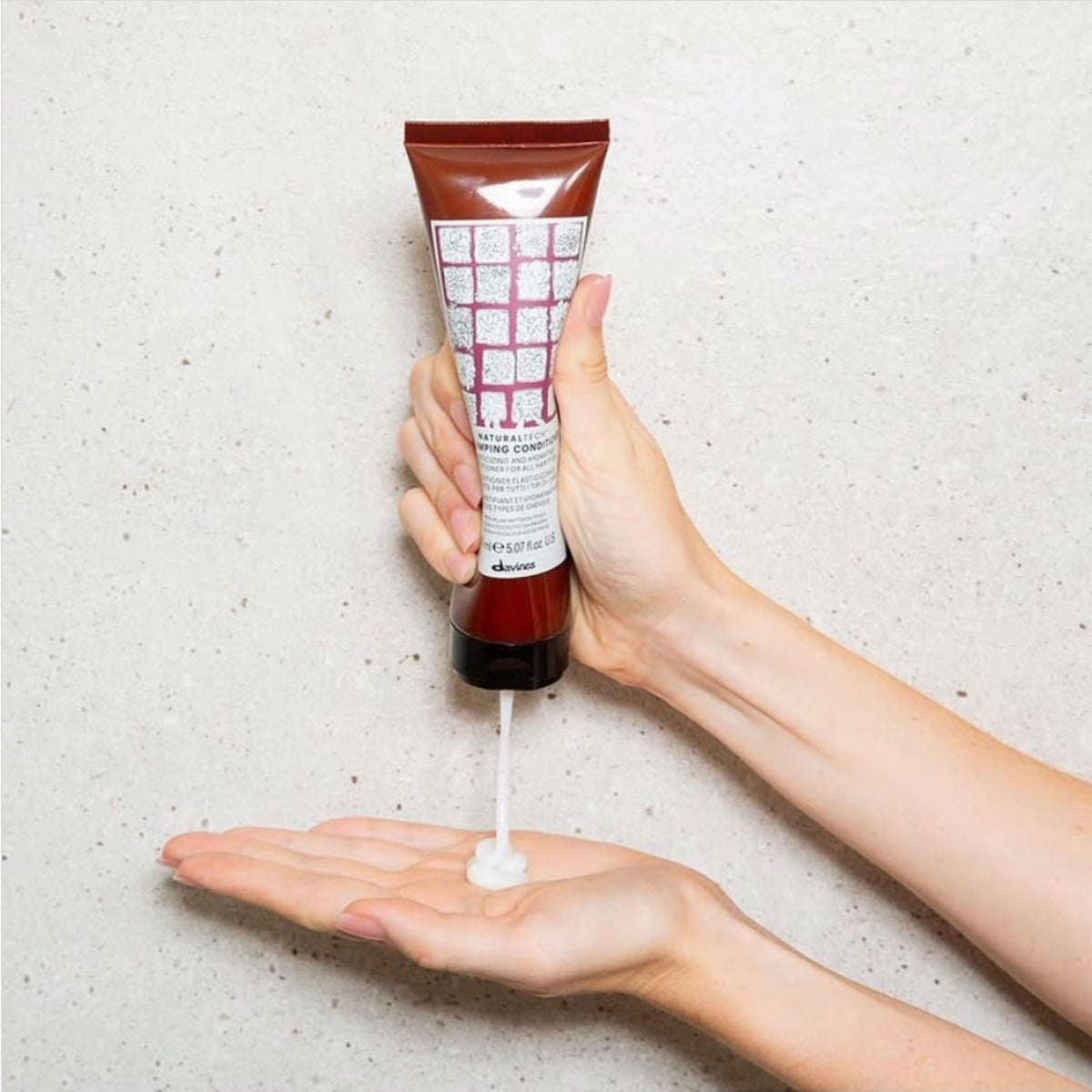 Davines applying conditioner to mid-lengths demonstrating detangling benefit