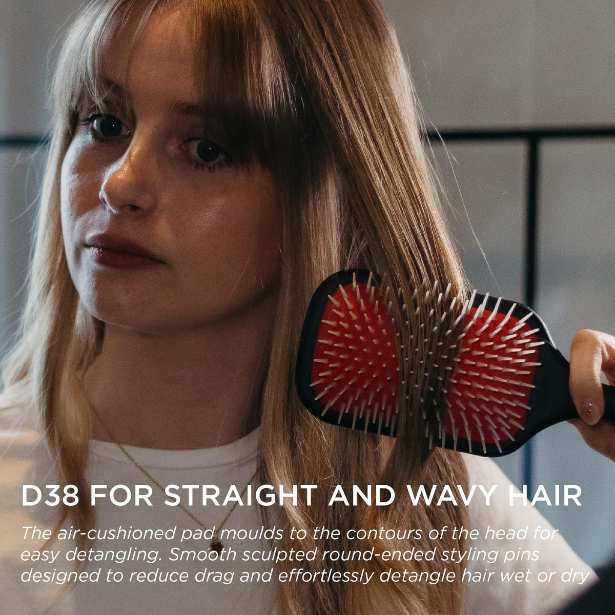 Denman brush held in hand showing scale and comfortable ergonomic grip