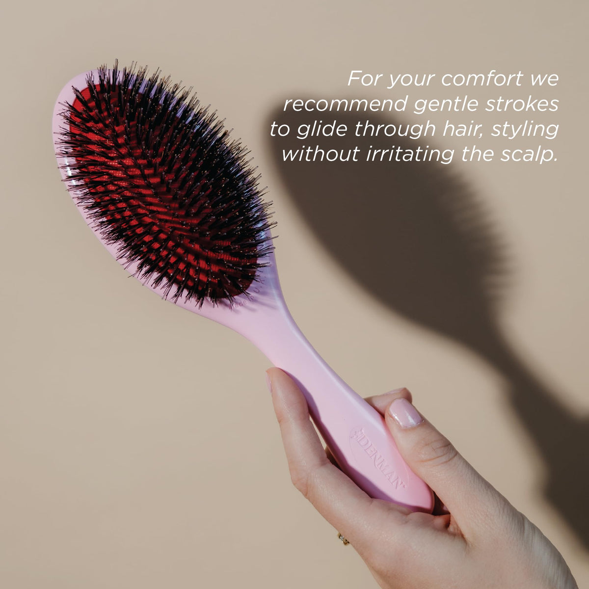 Denman Pink Crush brush placed on bathroom shelf indicating easy reach and stylish storage