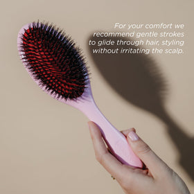 Denman Pink Crush brush placed on bathroom shelf indicating easy reach and stylish storage